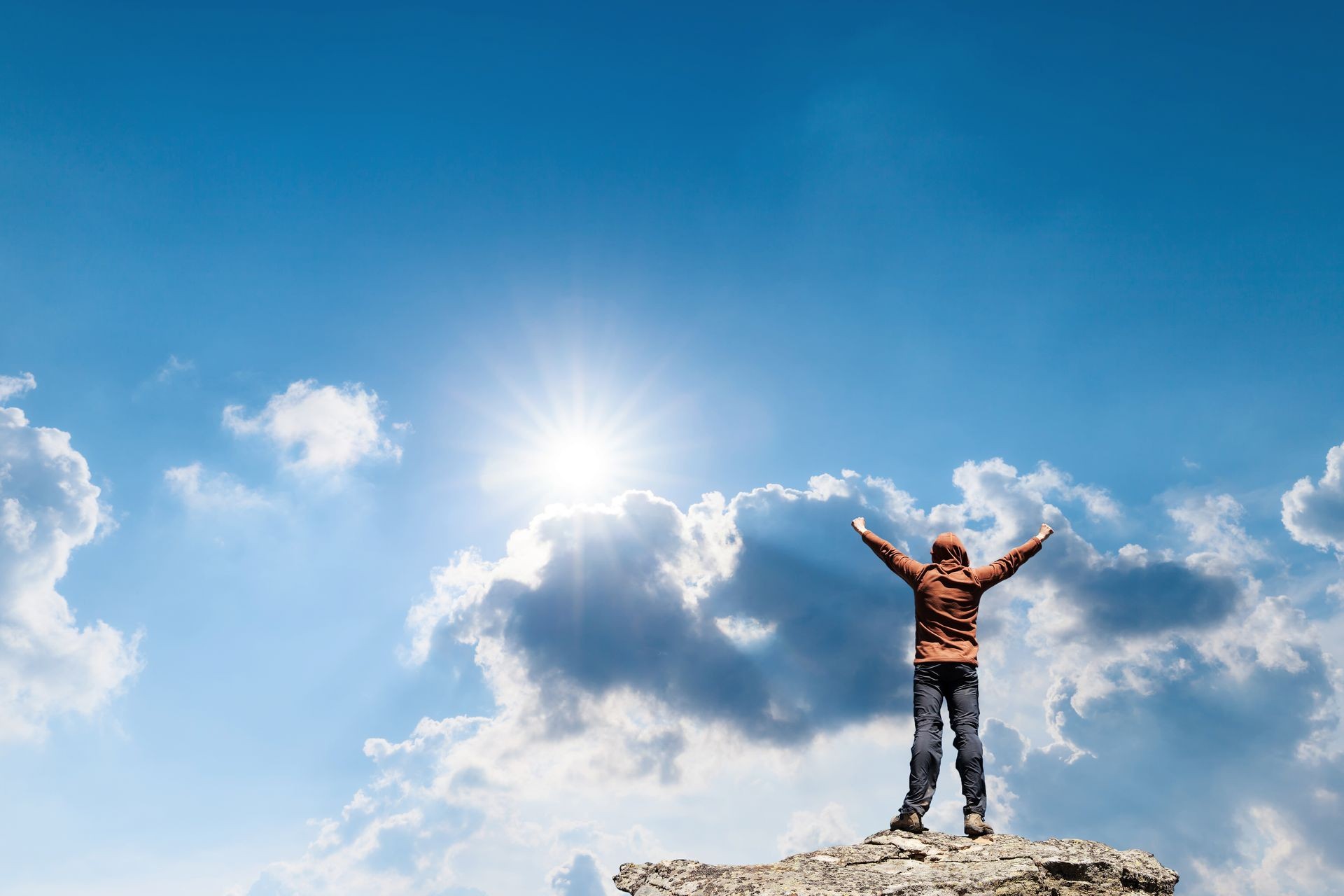 Man standing on the top of the mountain over blue sunny sky